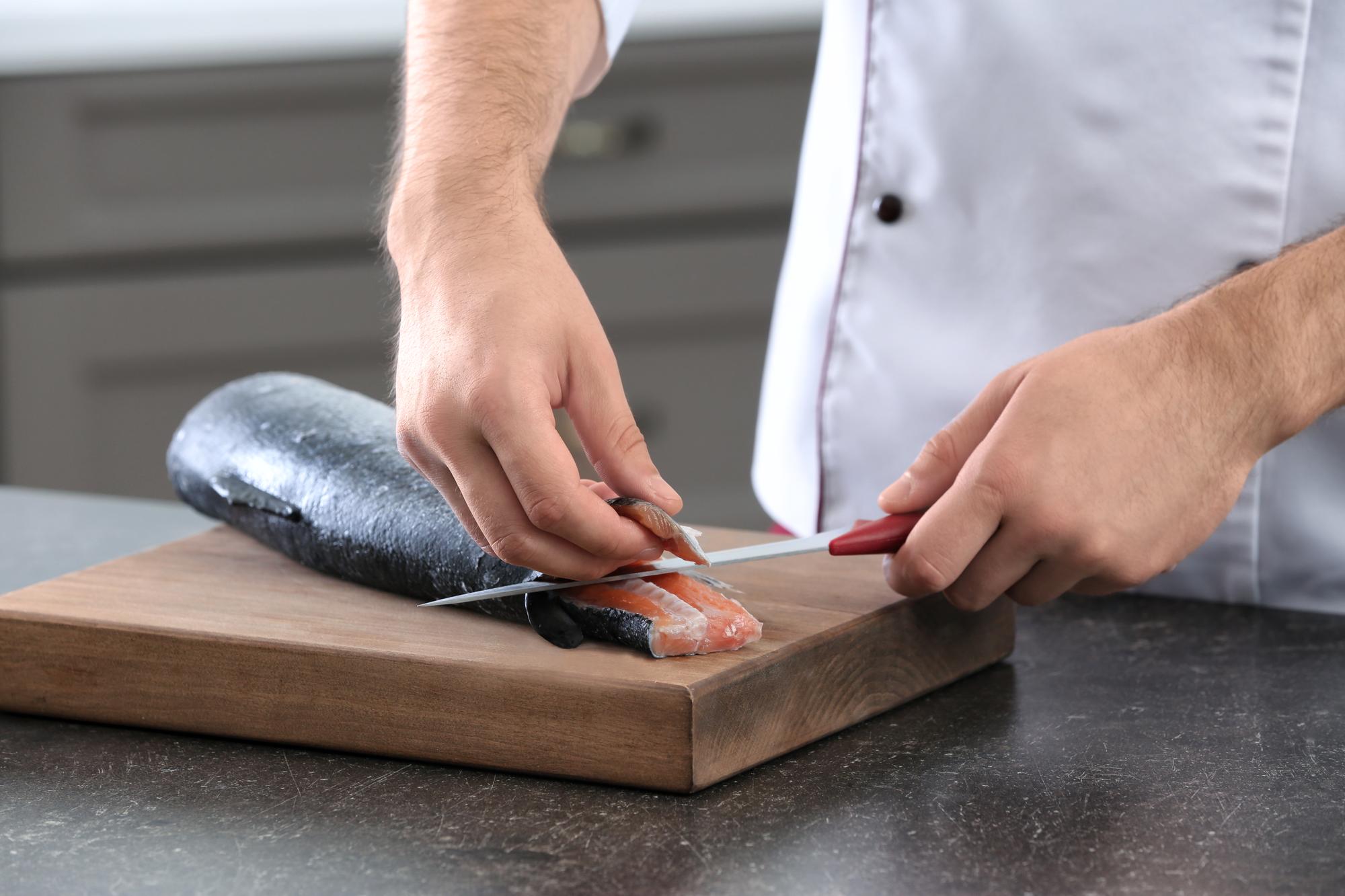 Primo piano su mani che sfilettano pesce